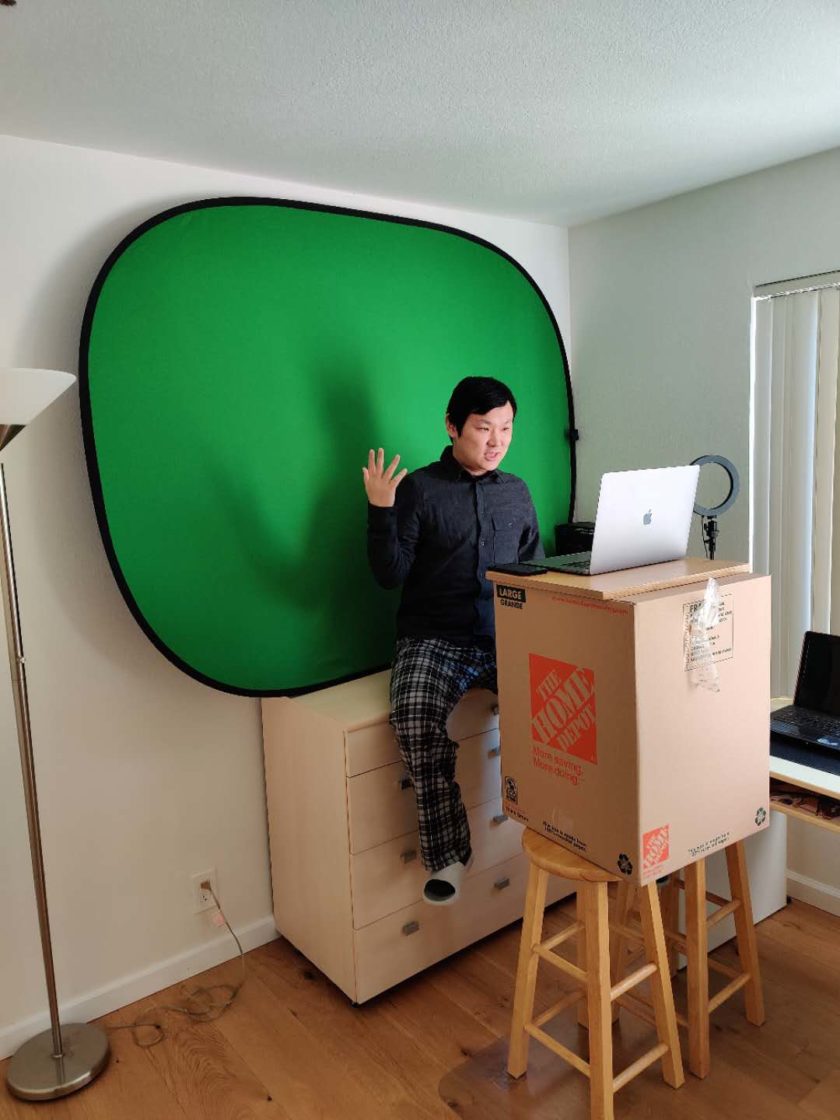 man sitting in front of green screen looking at computer