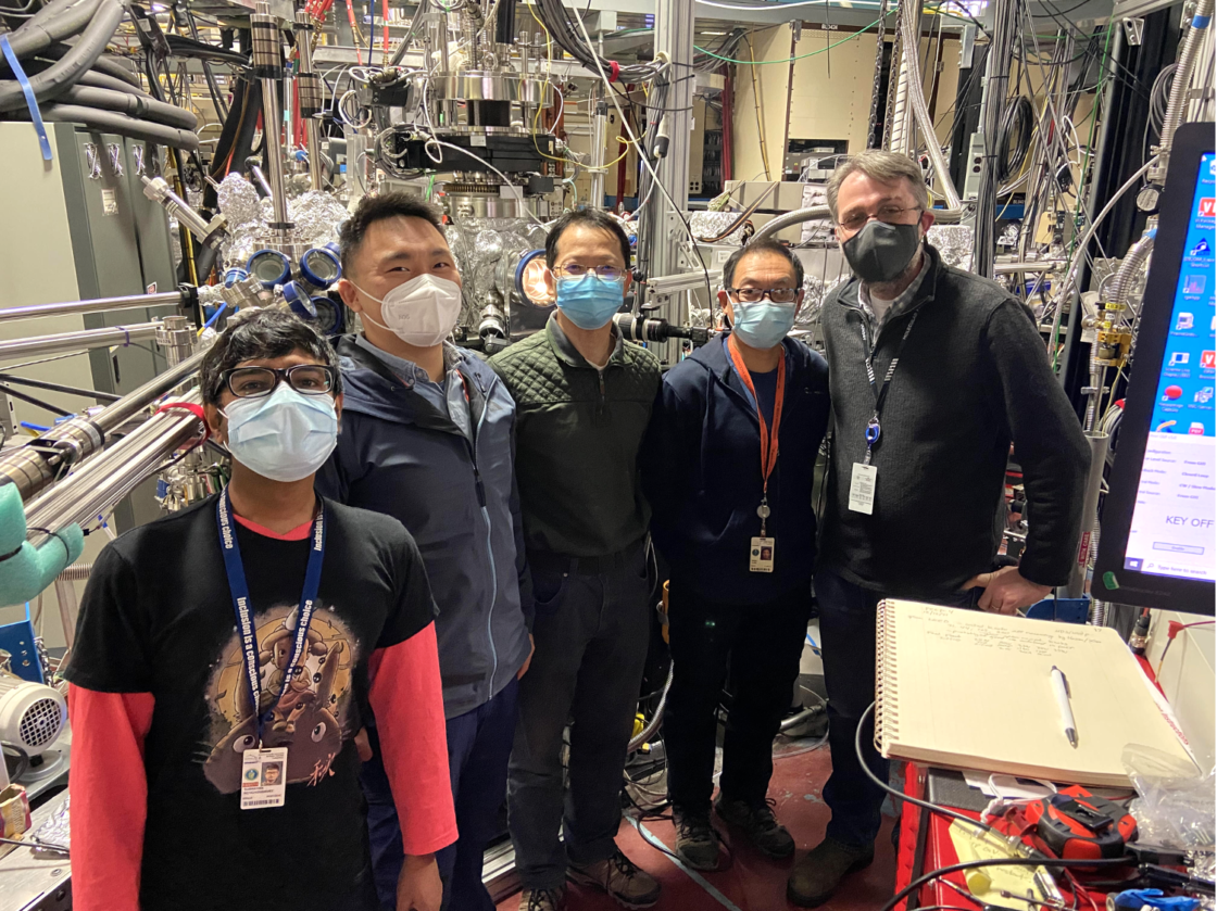 several people standing in front of scientific equipment wearing masks