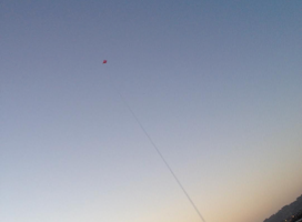 a kite flying in front of a sunset