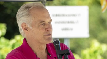 Man wearing bright pink polo shirt talking into a microphone