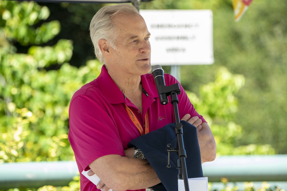 Man wearing bright pink polo shirt talking into a microphone