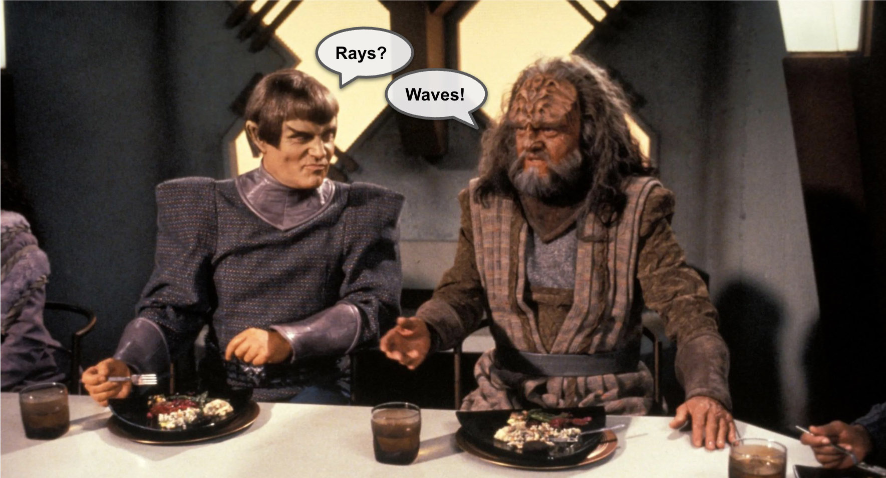 At a dinner table, a Romulan says “Rays?” and a Klingon says “Waves!”