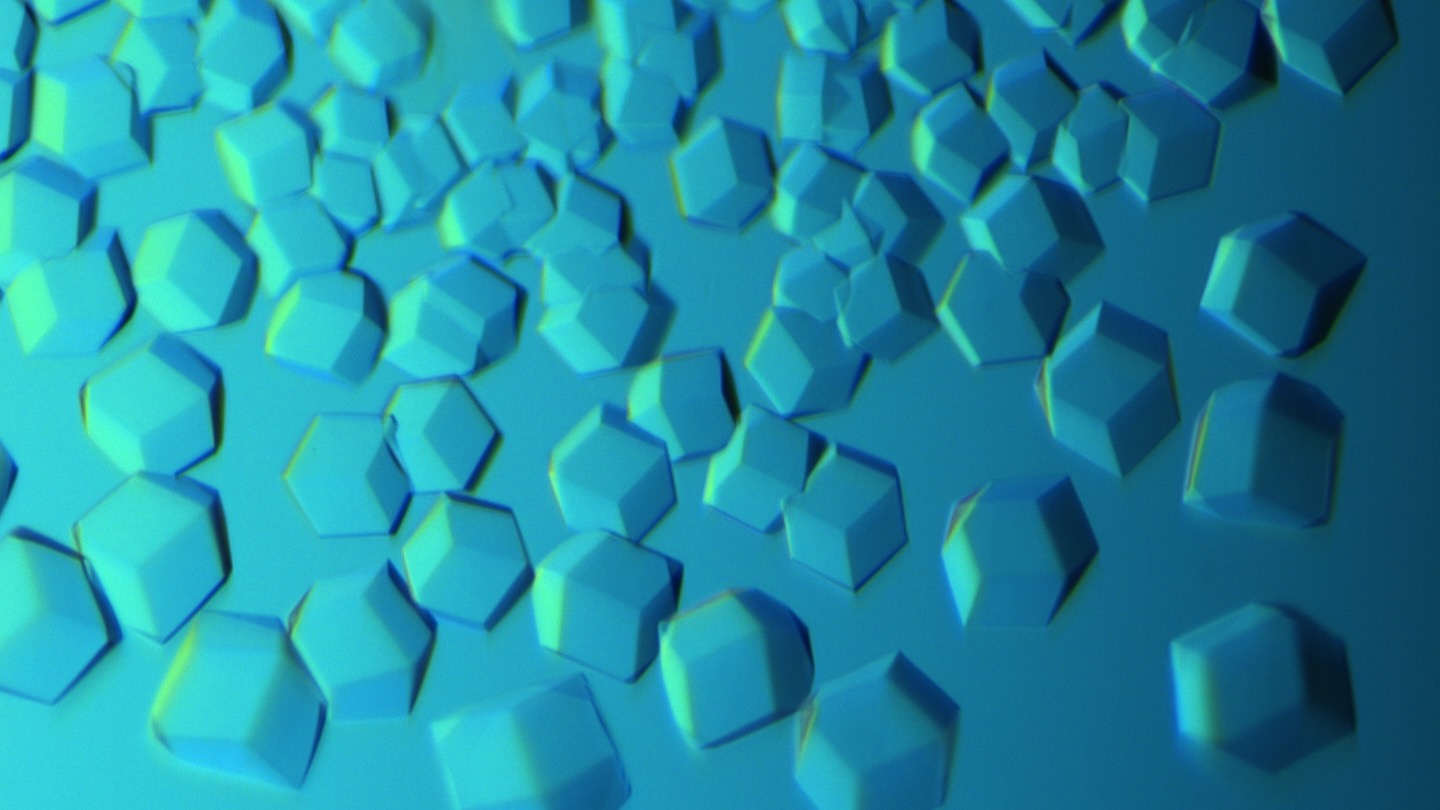 Cuboid crystals scattered across a blue background, lit from the upper right. 