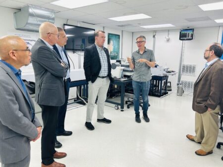 Several people standing in a group in a lab space, discussing.
