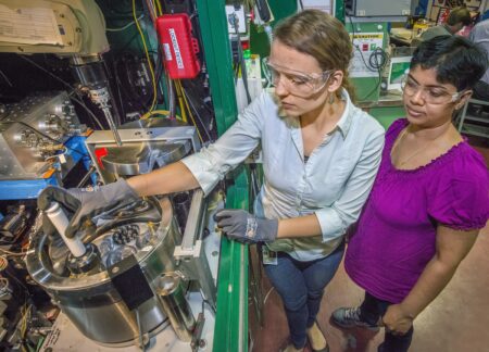 Two scientists wearing safety goggles and placing protein samples into a vacuum. 