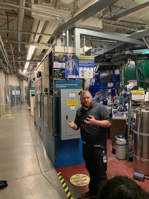 a man standing in front of a science poster and scientific equipment