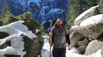 A man with a walking stick on a snowy mountain