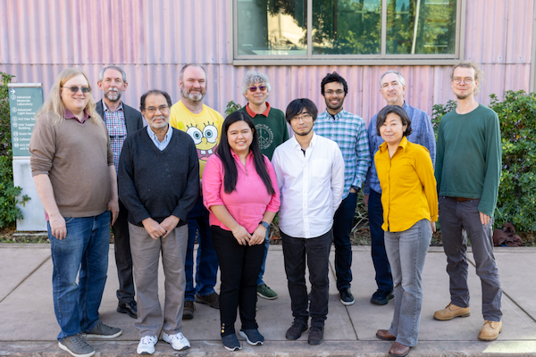 eleven people standing in front of pink building