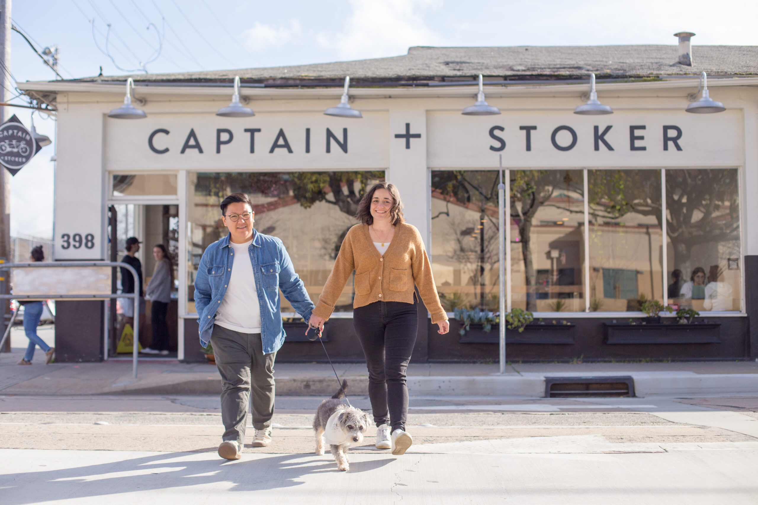 two women and a dog in front of a coffee shop