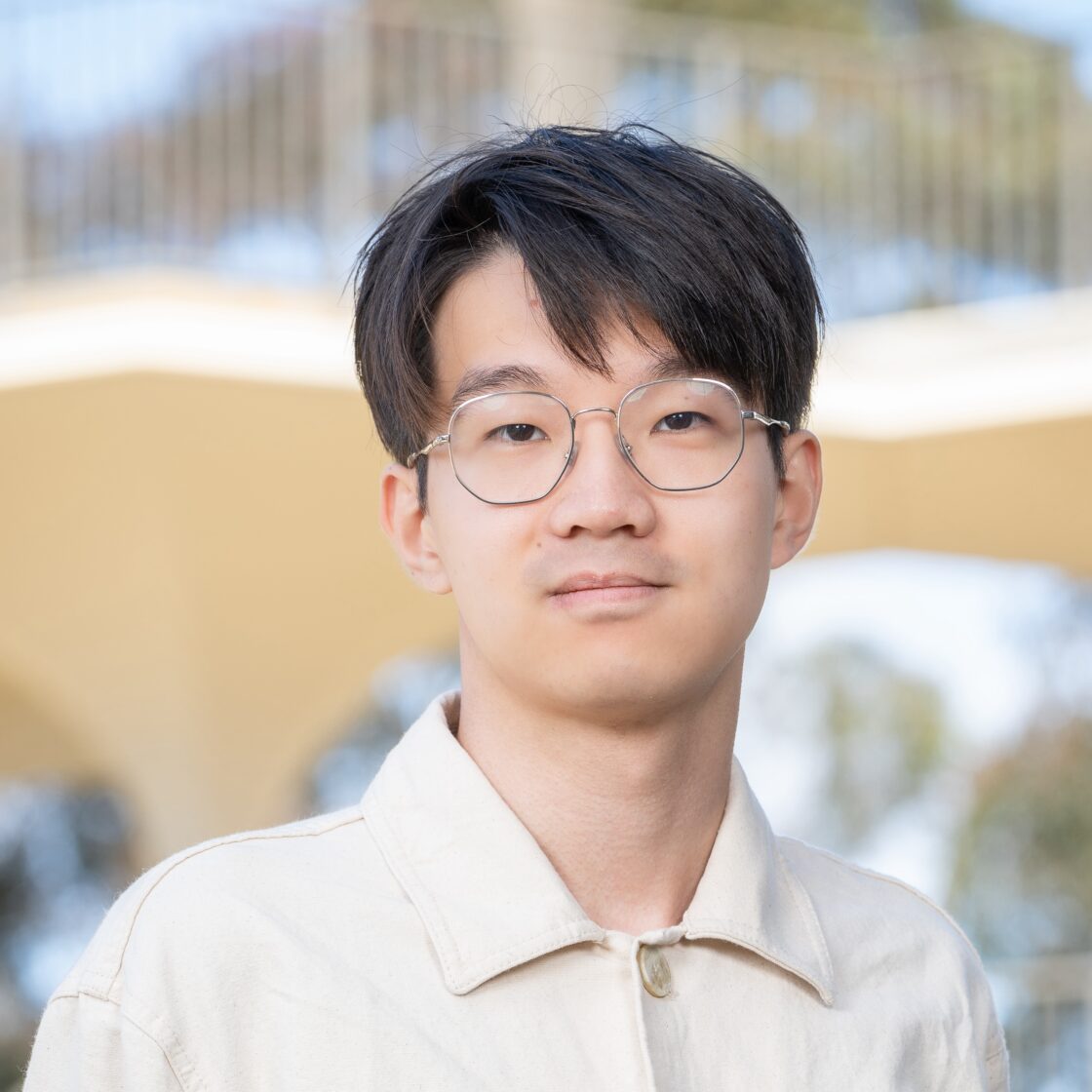 Profile photo of a man with glasses and a beige shirt.