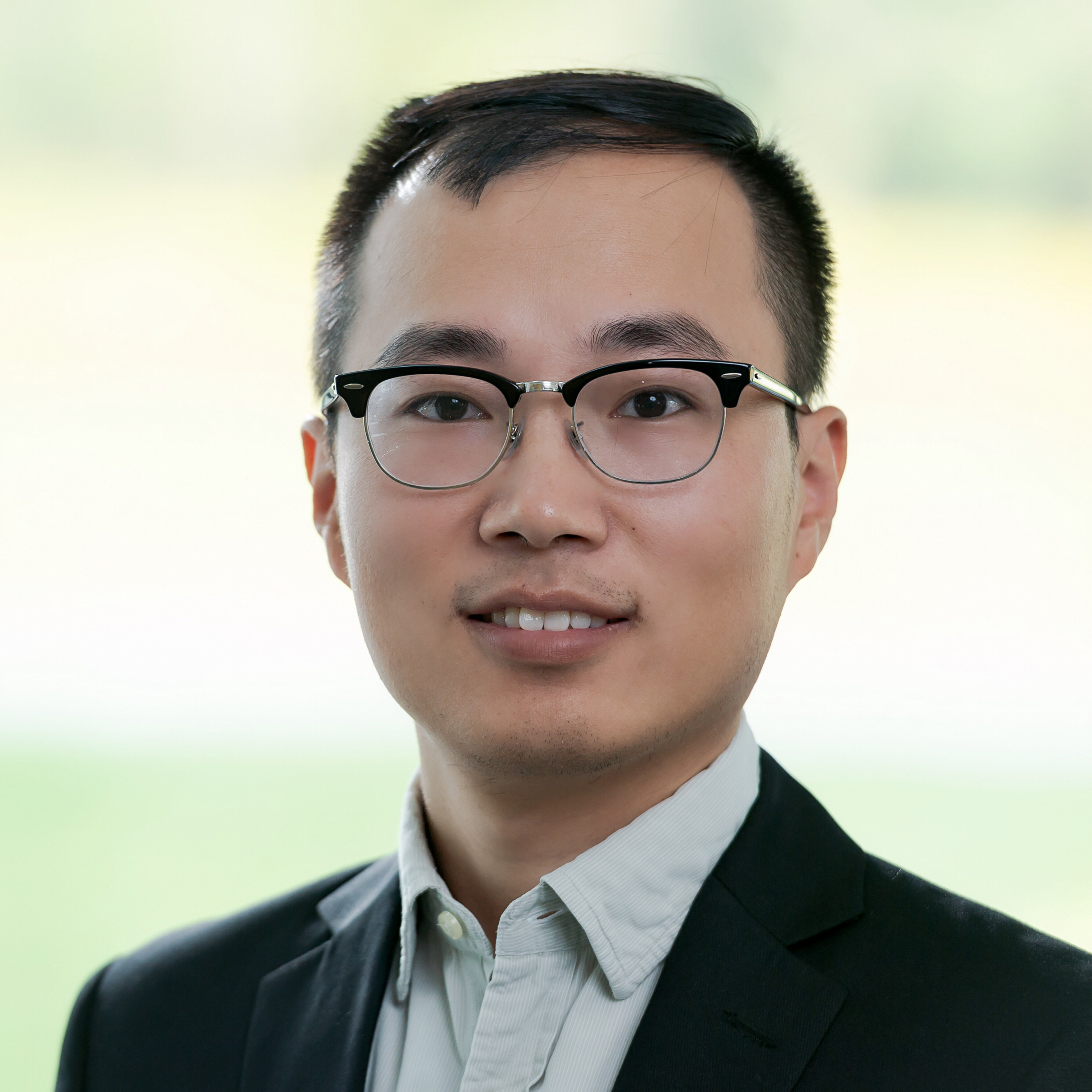 man wearing glasses, collared shirt, and dark jacket