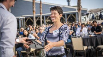 Person handing another person framed award certificate.