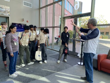 An adult talking to a group of teenaged scouts.